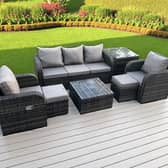 The seven-seater dark grey rattan garden furniture set includes reclining chairs, footstools and two tables.