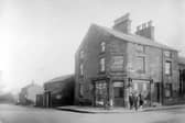 Weetwood Lane, left, at the junction with Moor Road. The shop on the corner was previously 'The Flower Box', owner Alice Greaves. Here it is a confectioners shop with advertisements for Cadburys' chocolate and Lyons cakes. A group of people pose outside the shop. Pictured in October 1930.