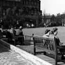 Looking south at the rest garden on Merrion Street. People sit on park benches arranged around a central square lawn. Behind is L. & M. Dombyack, furriers, at number 35 Wade Lane. Pictured in September 1943.
