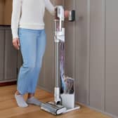 Shark’s Clean & Empty cordless vacuum returns to its charging dock after use, where collected dirt is transferred into a larger sealed base