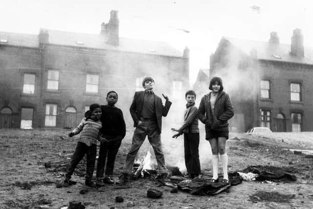 This photo from 1970 , entitled "Butch and Mates", shows a group of children of varying ages pictured as they play out on an area of cleared land in front of rows of terraced houses located in Servia Hill. They have lit a small "camp fire" which is blazing away behind them.