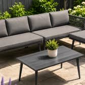 The five-seater garden furniture set includes a sofa, padded cushions, matching stool and wood-look table