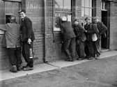 Miners are pictured circa 1950s collecting their wage tally from the first window, allowing them to draw their wages from the second window.