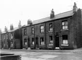 A young girl stands in the doorway of a house on Bagnall Street in December 1960.  The row of back-to-back terraced houses separated between numbers 27 and 29 by a yard housing shared outside toilets.