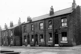 A young girl stands in the doorway of a house on Bagnall Street in December 1960.  The row of back-to-back terraced houses separated between numbers 27 and 29 by a yard housing shared outside toilets.