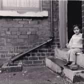 A toddler sits on the steps of his home on Lascelles Road in January 1988.