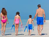 A happy family of mother, father and child, a daughter, walking in swimming costumes on a sunny beach
