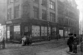 The junction of New Market Street with Kirkgate former premises of Tiger Stores. Statue of tiger sited above doorway. Women, men and children in period dress pose on corners of roadside. Pictured in July 1907.