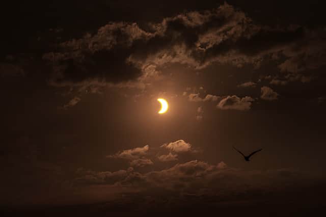 Birds fly past a partial solar eclipse, seen over Liverpool Bay from Crosby Beach on 12 August 2026 in Liverpool, United Kingdom.
