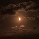 Birds fly past a partial solar eclipse, seen over Liverpool Bay from Crosby Beach on 12 August 2026 in Liverpool, United Kingdom.
