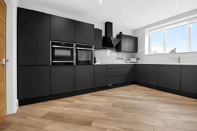 The contemporary dining kitchen brings together sleek cabinetry, quartz worktops, generous dining space and a large picture window overlooking far-reaching countryside views.
