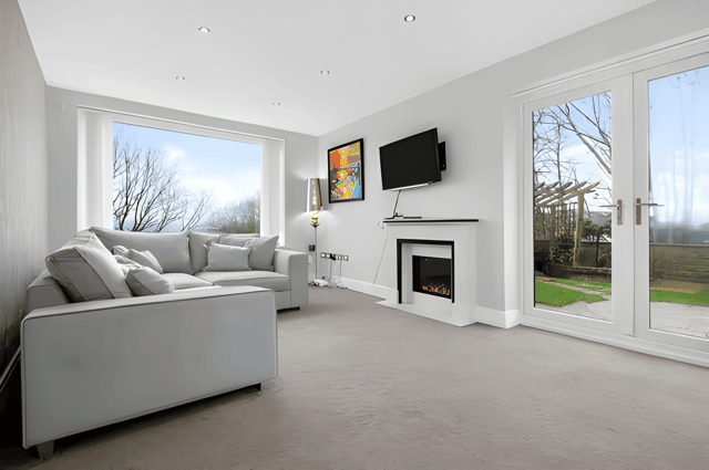 A feature fireplace gives the elegant living room a focal point, while French doors connect the reception space with the tranquil garden beyond.