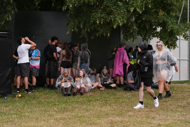 Festivalgoers shelter from the rain at Bramham Park on Saturday