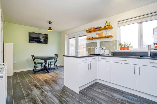 A contemporary kitchen with breakfast bar and dining area forms the centrepiece of the home and opens towards the garden