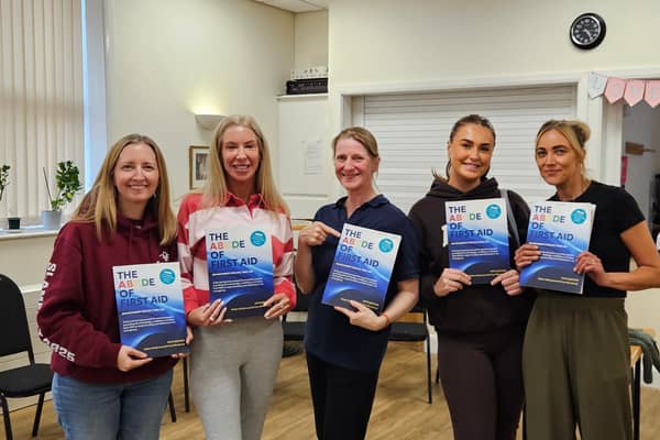  Helen Underwood with learners from a recent Paediatric First Aid course holding the newly printed fifth edition of The ABCDE of First Aid
