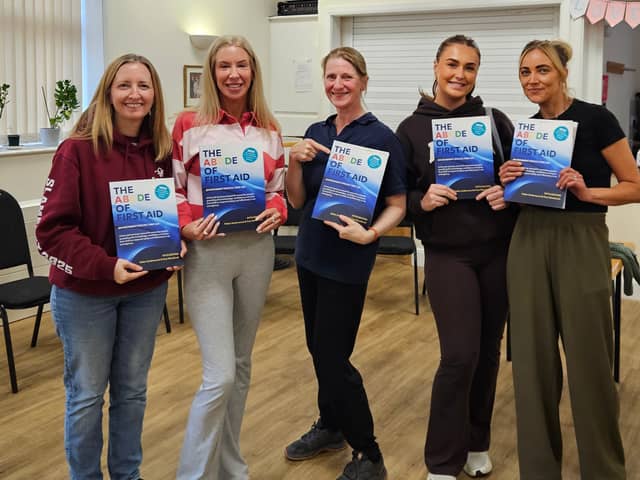  Helen Underwood with learners from a recent Paediatric First Aid course holding the newly printed fifth edition of The ABCDE of First Aid