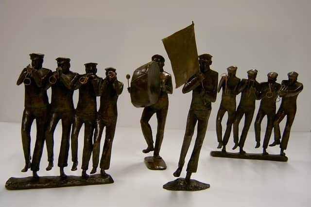 A collection of detailed bronze sculptures by Betty Miller depicting a marching brass band, featuring horn players, a bass drummer, and a flag bearer