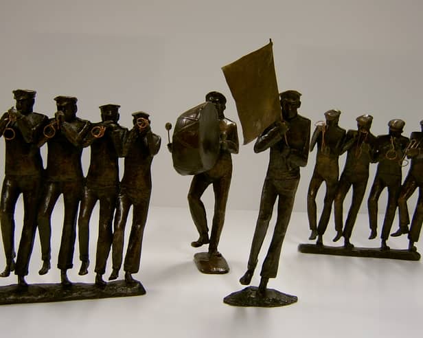 A collection of detailed bronze sculptures by Betty Miller depicting a marching brass band, featuring horn players, a bass drummer, and a flag bearer