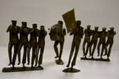 A collection of detailed bronze sculptures by Betty Miller depicting a marching brass band, featuring horn players, a bass drummer, and a flag bearer