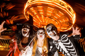 Spooky costumed characters strike a pose in front of a spinning fairground ride during Lightwater Valley's Frightwater Valley Halloween event