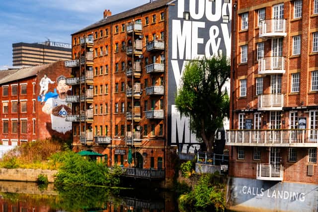 Offices and murals reflected in the still water of the River Aire in Leeds.