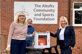 Tracey Holmes and David Norris receive the defibrillator from Taylor Wimpey Sales Executive Michelle Mullooly 
