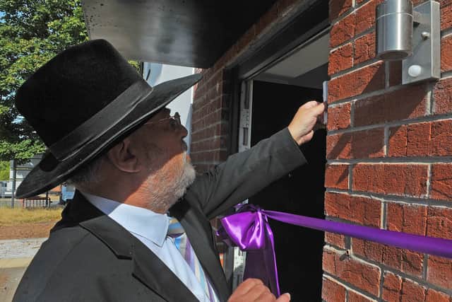 Rabbi Anthony Gilbert affixes a mezuzah to one of the new LJHA homes in north Leeds