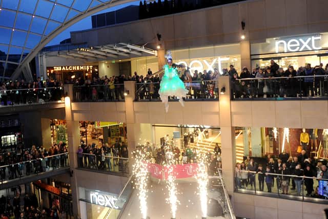 A violinist swings from the roof at Trinity Leeds.
