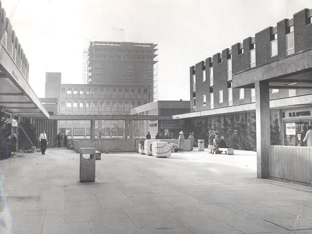 The upper precinct of Seacroft Shopping Centre, with a 17 storey block of flats in the background.