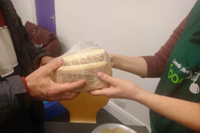 A volunteer at the foodbank at Oak Church hands over a loaf of bread.