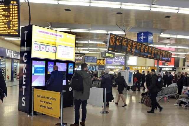 Passengers check for train information at Leeds station.