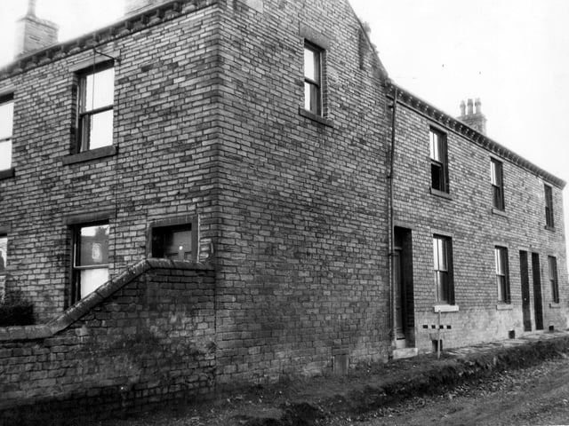 Brick-built terraced houses on 132 Street Lane adjacent to Reedsdale Gardens. The road is unmade in front of the properties.