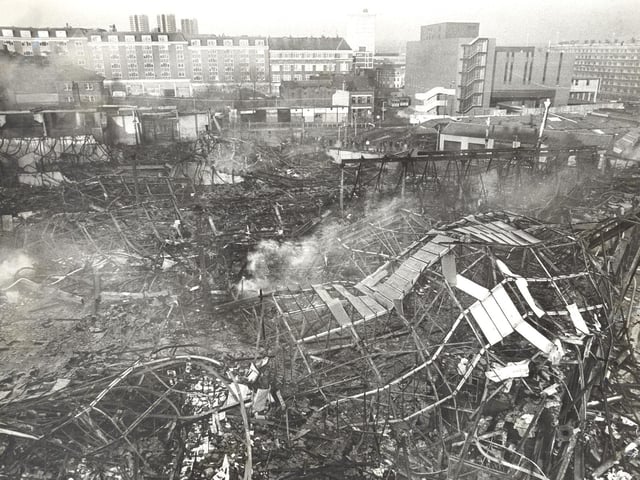 Smoke rises from the ruins of tangled girders.