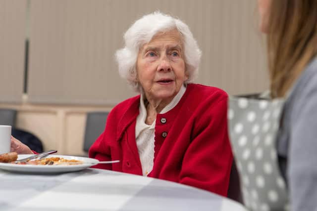 Audrey Hardy, 90, enjoys a chat with a volunteer over her breakfast.