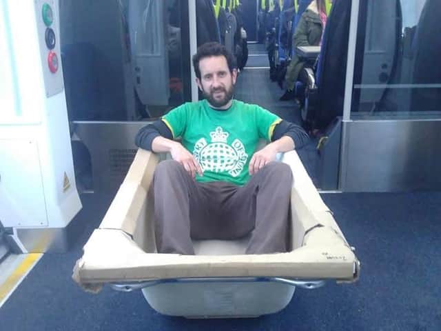 Green Party councillor Ed Carlisle is pictured transporting a bath tub from Lancashire to Leeds on a Northern train