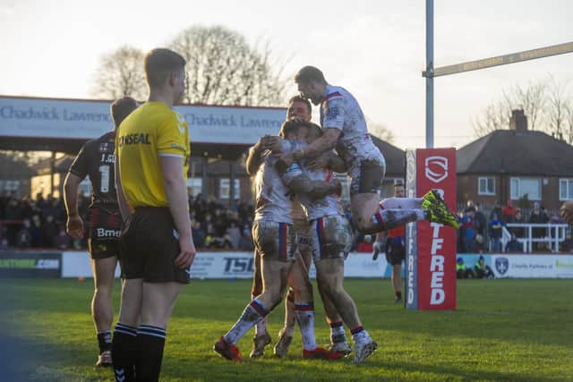 Tom Johnstone is mo0bbed after scoring the clinching try for Wakefield