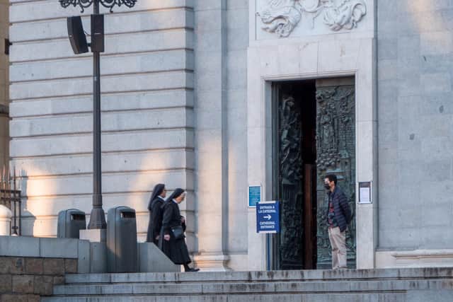 A face-masked tourist observes two nuns entering Almudena Cathedral in Madrid. Photo credit: James Dacey