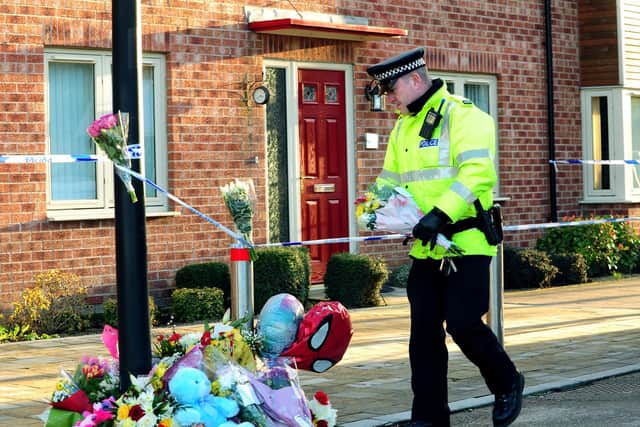 An officer lays flowers outside the house in Allerton Bywater where Geraldine Newman and her two children were killed. Picture: Jonathan Gawthorpe