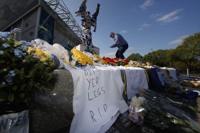 A fan looks on as tributes gather outside Elland Road in memory of Norman Hunter.