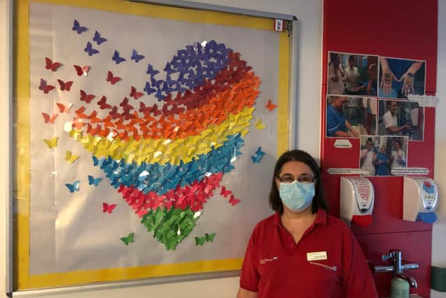 Play specialist Emma Marshall with her artwork on the wall of the congenital heart unit at Leeds General Infirmary.