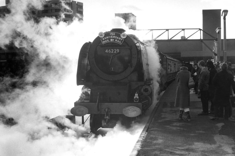 As the steam clears, the Duchess of Hamilton locomotive is revealed in all her former glory. She was at Leeds City Station to mark the 150th year of transported mail deliveries.