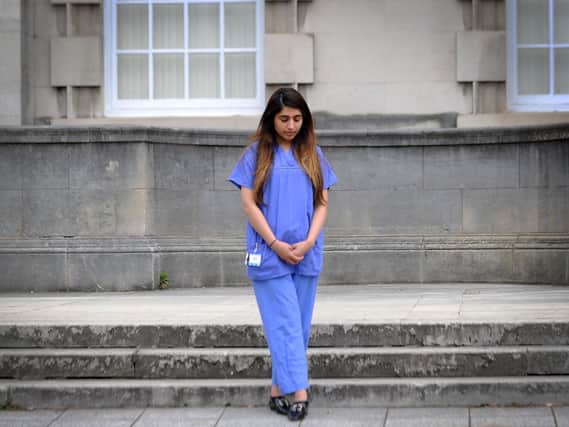 A health worker pauses to remember those who have lost their lives in Millennium Square, in Leeds.
