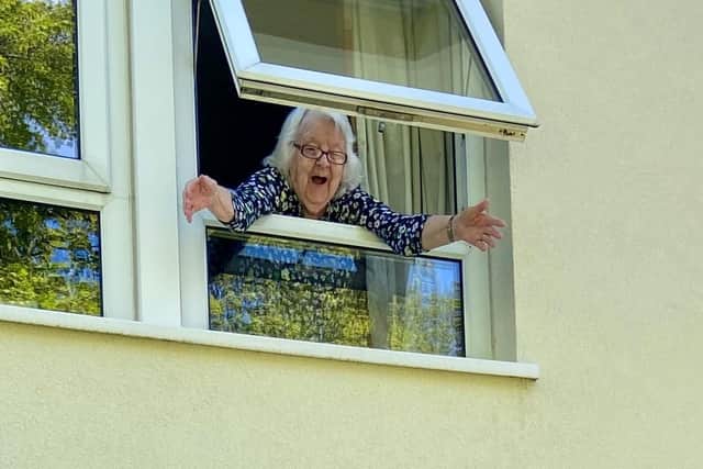 A delighted Joan Cartwright says hello from the window of her flat in Horsforth.