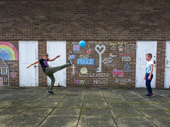 Youngsters Connor and Riley Piggott play by the wall which residents have decorated with chalk during the lockdown by their homes on the Elmetes estate in Roundhay.