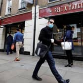 A man wearing PPE (personal protective equipment) passes customers queuing to enter a recently re-opened Pret-A-Manger shop which had originally closed-down due to the COVID-19 pandemic in London (Photo: TOLGA AKMEN/AFP via Getty Images) Copyright: Getty Images