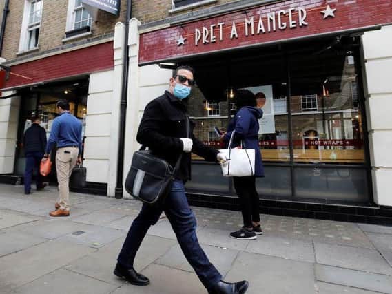 A man wearing PPE (personal protective equipment) passes customers queuing to enter a recently re-opened Pret-A-Manger shop which had originally closed-down due to the COVID-19 pandemic in London (Photo: TOLGA AKMEN/AFP via Getty Images) Copyright: Getty Images