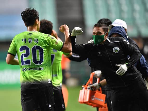NEW NORMAL - Jeonbuk Hyundai Motors' Lee Dong-gook celebrates his goal with his team staff against Suwon Samsung Bluewings during the opening game of South Korea's K-League. Pic: Getty.