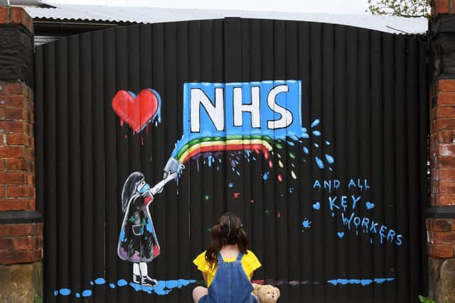 A young girl admires a mural made to honour the work of the NHS and key workers.