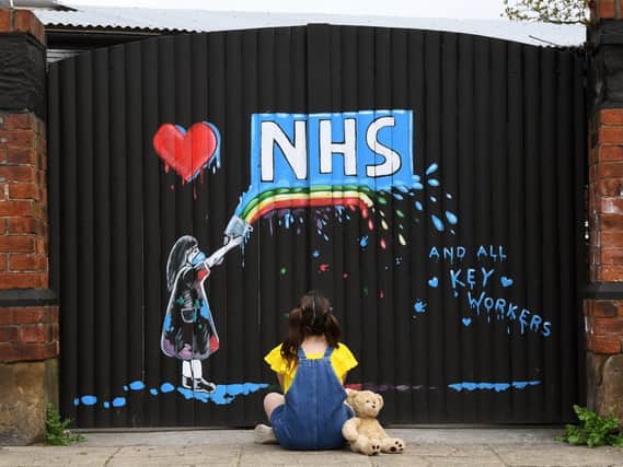 A young girl admires a mural made to honour the work of the NHS and key workers.