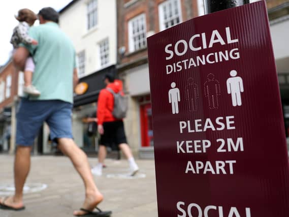 People walk past a social distancing sign, ahead of the re-opening of non-essential retailers in England on June 15. Photo: PA